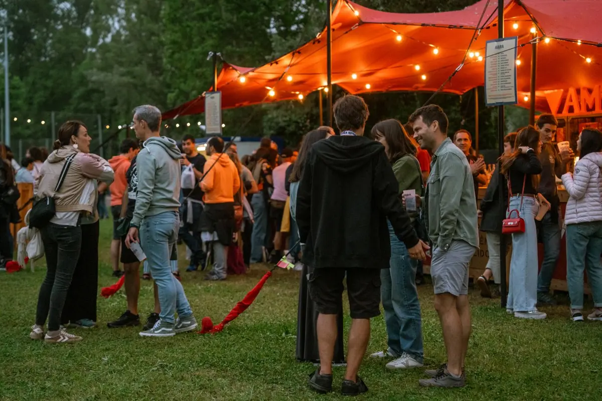 Guests socializing under a tent with string lights at an outdoor party