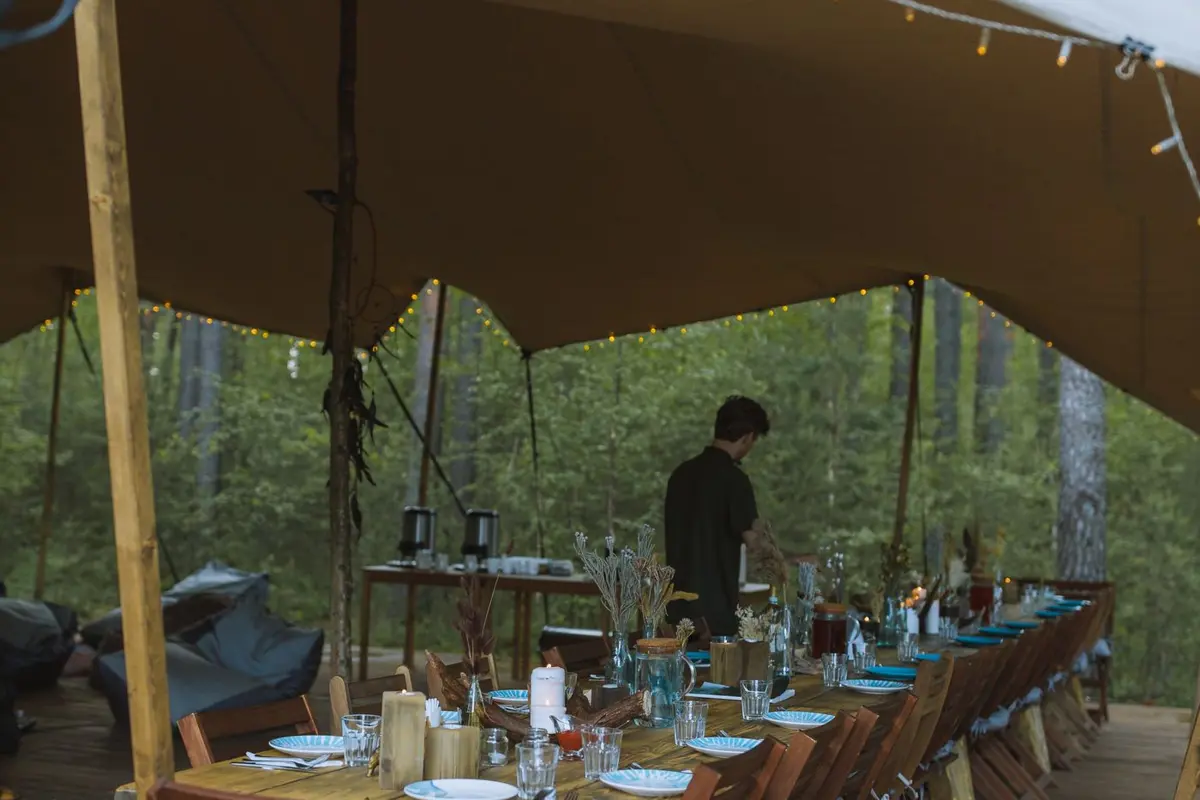 Long tables set for dinner under an outdoor tent