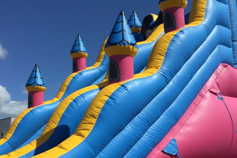 Tall inflatable slide with colorful turrets against a blue sky