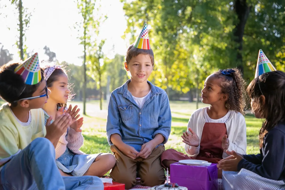 Kids in party hats celebrating a birthday outdoors