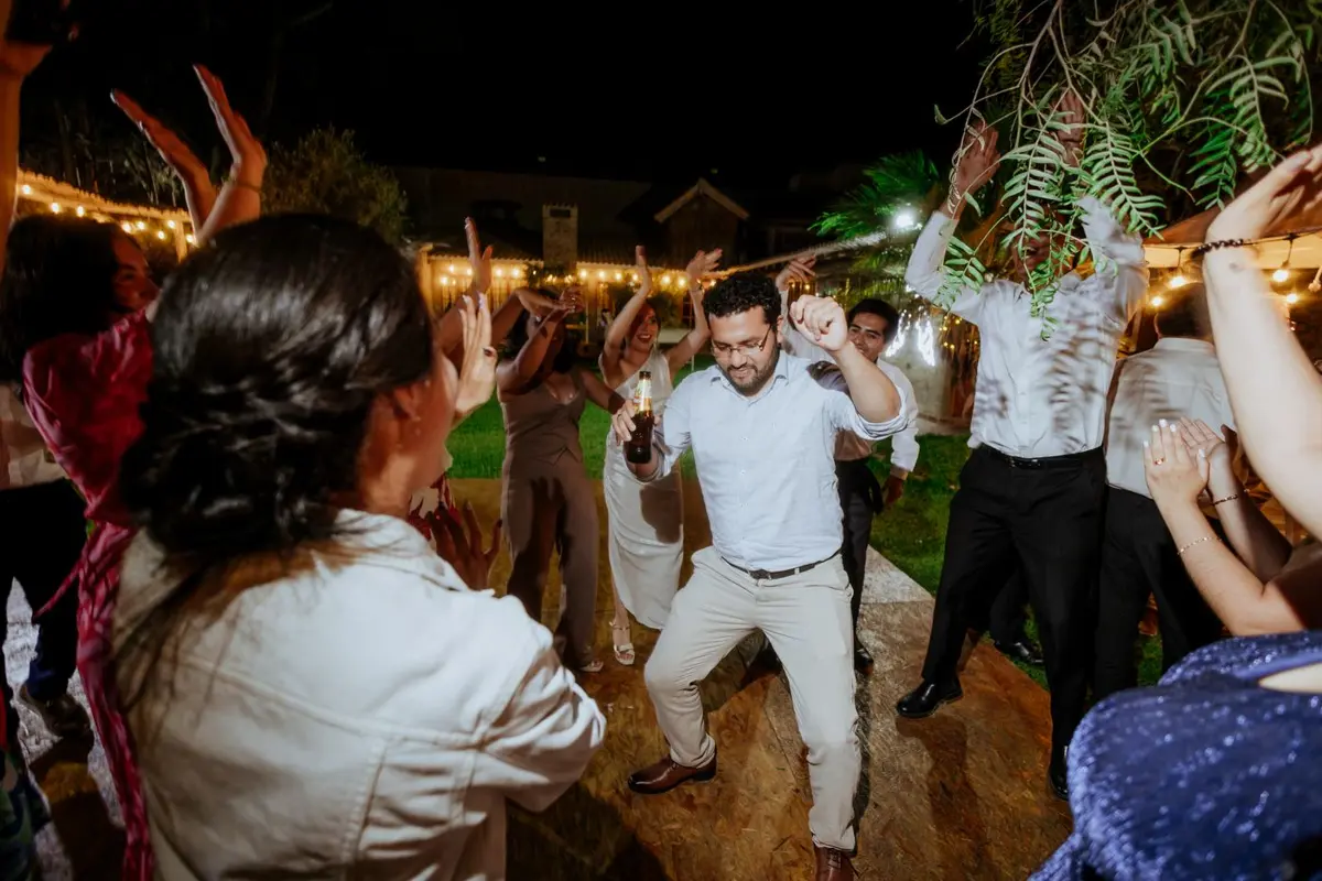 Guests dancing and celebrating at an outdoor party under string lights at night