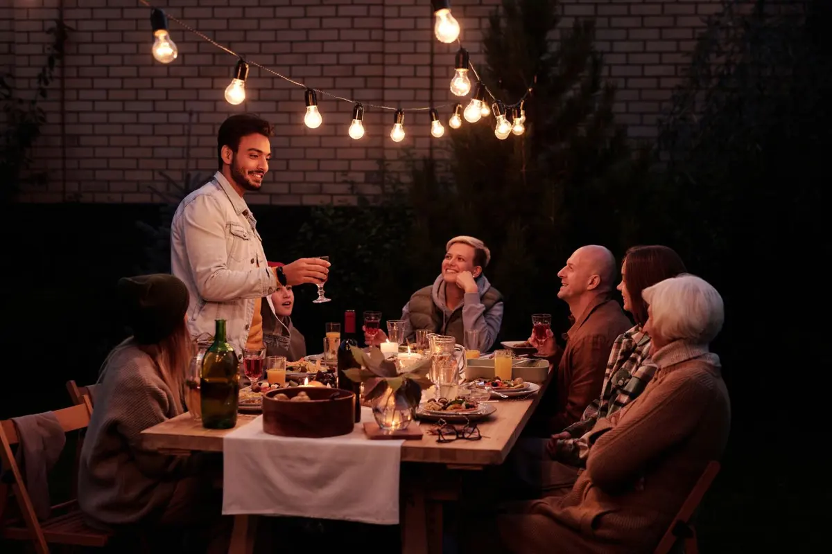 Family dinner party outdoors under string lights