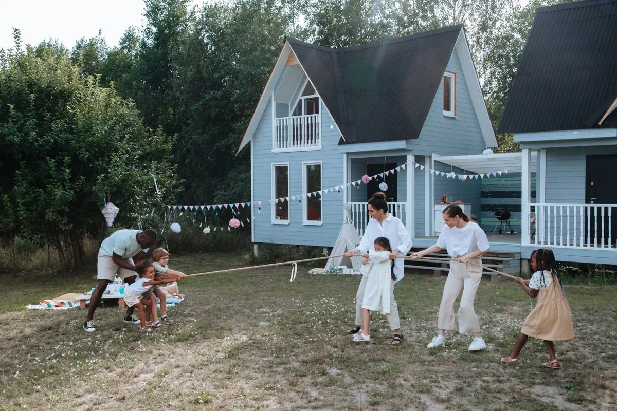 Kids and adults playing tug of war in front of neighborhood houses