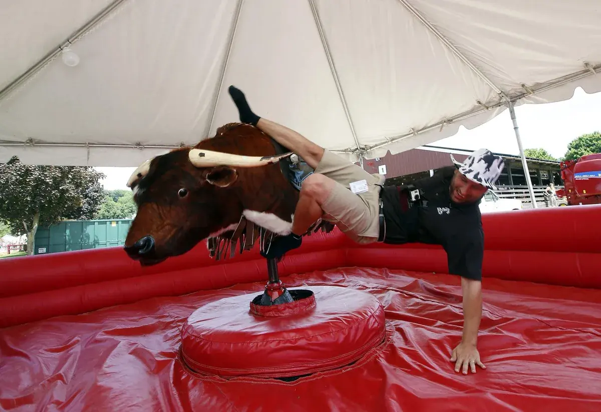Rider on The Beast mechanical bull under a tent with an inflatable safety ring