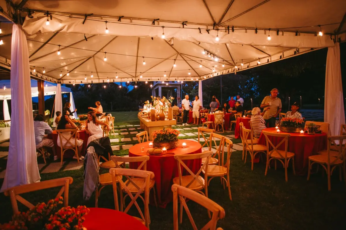 Guests dining under a tent lit with string lights in the evening