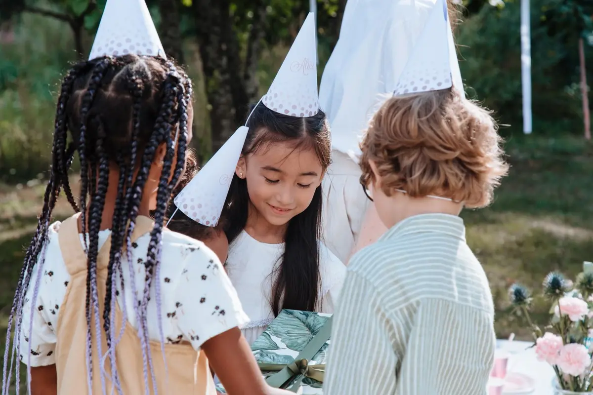 Kids in party hats at an outdoor birthday party