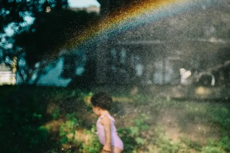 Young child playing in a backyard sprinkler on a summer day